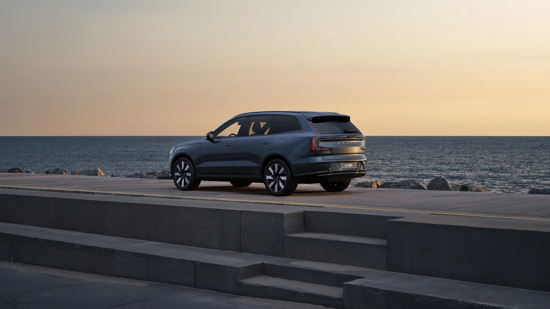 Volvo EX90 Denim Blue на набережной на закате